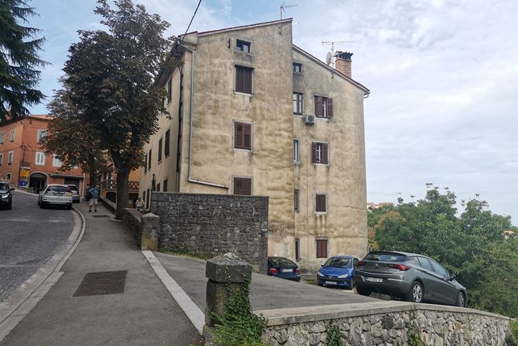 Zgrada s parkingom na usponu za stari grad s niskim zidićem